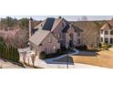 Spacious brick home with an attached garage, mature trees, and a lush lawn at 390 Falls Point Trl, Johns Creek, GA 30022