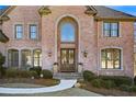 Elegant brick home featuring an arched entryway and decorative front door at 390 Falls Point Trl, Johns Creek, GA 30022