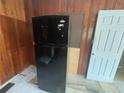 Black refrigerator sits against the wall, next to a wooden cabinet and door at 1907 Langston Sw Ave, Atlanta, GA 30310