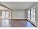 Open living area with hardwood floors, neutral walls, and natural light from large windows at 1064 Wenham Ln, Lawrenceville, GA 30044