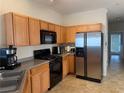 The kitchen offers wood cabinets, black appliances, a stainless fridge, and tile floors at 3134 Imperial Sw Cir, Atlanta, GA 30311