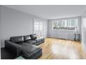 A modern living room with hardwood floors and a black sofa features natural light from a large window at 215 Piedmont Ave # Apt 402, Atlanta, GA 30308