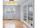 Bright living room features hardwood floors, a window with city views, and stylish French doors at 215 Piedmont Ave # Apt 402, Atlanta, GA 30308