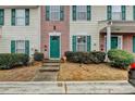 Close-up of a townhouse entrance featuring a green door, brick accents, and well-maintained landscaping at 3154 Panthers Trce, Decatur, GA 30034