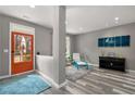 Cozy living room with gray walls, wood floors, a turquoise accent chair, and a vibrant orange front door at 313 Revolution Dr, Peachtree City, GA 30269