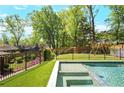 Backyard pool with turf, surrounded by black fencing and lush greenery, perfect for outdoor fun at 2922 Parkridge Ne Dr, Brookhaven, GA 30319