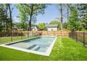 Backyard pool with turf, framed by black fencing, and lush greenery, creating an inviting oasis at 2922 Parkridge Ne Dr, Brookhaven, GA 30319