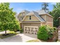 Exterior shows side entry garage of home surrounded by landscaping, mature trees and a blue sky at 1907 Haven Park Se Cir, Smyrna, GA 30080