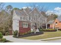 View of home showing brick and gray siding, well manicured lawn, and deck leading from driveway at 2064 Democracy Dr, Buford, GA 30519