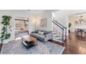 Comfortable living room featuring a modern sofa, area rug, and staircase at 565 Ashvale Overlook, Alpharetta, GA 30005