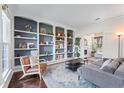 Bright living room with a decorative rug, and built in shelving unit painted gray and white with decorations at 565 Ashvale Overlook, Alpharetta, GA 30005