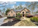 Elegant brick home showcasing meticulous landscaping, mature trees, and stone accents at 6030 Chimney Springs Rd, Buford, GA 30518
