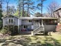 Back exterior of home with a screened porch, large yard and a stone patio with colorful chairs at 6275 Hunting Creek Rd, Atlanta, GA 30328