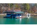 View of boat dock featuring multiple boat slips and a sundeck on top, situated on a serene body of water at 7565 Heard Rd, Cumming, GA 30041