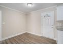Bright dining room with wood-look flooring, crown molding, and white door to the exterior at 542 Oak Hills Sw Rd, Mableton, GA 30126