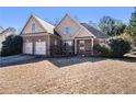 Inviting two-story house with brick accents, a cozy front porch, and a manicured lawn in a sunny setting at 8000 Abington Dr, Locust Grove, GA 30248