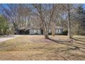 Wide shot of the home featuring a grey exterior, a covered parking area, and a generous front yard at 3759 Rosemary Se Ln, Conyers, GA 30013