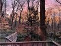 View from deck of a wooded backyard at sunset with pink, purple, and orange highlights at 566 Hickory Hills Ct, Stone Mountain, GA 30083