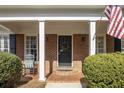 Inviting front porch with brick columns, a rocking chair, and a stylish front door with decorative wreath at 18 Brandon Ridge Dr, Sandy Springs, GA 30328