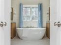 Modern bathroom featuring a freestanding tub, soothing blue accents, and natural light at 11120 Surrey Park Trail, Johns Creek, GA 30097