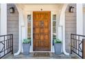 Inviting front entrance with a wood door, decorative plants, and a 'Home Sweet Home' mat at 11120 Surrey Park Trail, Johns Creek, GA 30097