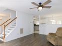 Living room with hardwood floors, stairs, and ceiling fan provides access to other living spaces at 554 Samaritan Dr, Cumming, GA 30040