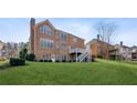 Backyard view of a brick home showcasing a spacious lawn, deck and multiple windows for natural light at 3690 Millwater Xing, Dacula, GA 30019