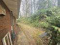 Brick facade and overgrown side yard with brick walkway and verdant foliage at 1288 N Emory N Pl, Atlanta, GA 30306