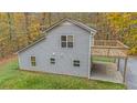 View of the back of a gray home with a wooden deck and a concrete patio underneath at 115 Bruce Rd, Douglasville, GA 30134