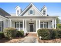 Inviting front porch with white columns, decorative lighting, and manicured shrubbery enhancing curb appeal at 155 Rose Creek Dr, Covington, GA 30014