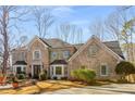 Elegant two-story brick home showcases a landscaped front yard and traditional architecture with green shutters at 9465 Mistwater Close, Roswell, GA 30076