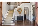 Inviting foyer featuring hardwood floors, staircase with patterned carpet, and a decorative mirror over a console table at 9465 Mistwater Close, Roswell, GA 30076