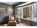 Cozy study with custom paneled walls, leather chair, ottoman, bay window with shutters, and hardwood flooring at 9465 Mistwater Close, Roswell, GA 30076