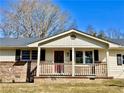 Inviting front porch with brick foundation, white railings, and a red front door entrance at 1091 Mountain View Nw Rd, Conyers, GA 30012