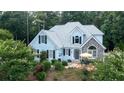 Charming two-story home featuring blue siding, black shutters, and a stone-accented entrance with a yellow umbrella on the patio at 210 Wrights Mill Way, Canton, GA 30115