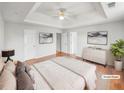 Virtually staged main bedroom with a tray ceiling, ceiling fan, and an ensuite bathroom entrance, with hardwood floors at 4565 Bridle Point Pkwy, Snellville, GA 30039