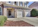 Close-up of a home's entrance featuring a two-car garage, brick accents, and a well-manicured front yard at 1384 Stone Bay Sw Dr, Atlanta, GA 30331