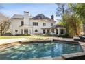 Relaxing backyard pool featuring a stone border, an outdoor patio, mature trees, and an exterior view of the home at 4399 Jett Nw Pl, Atlanta, GA 30327