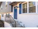 Close-up of the front entrance with a blue door, white brick, black railing and blue shutters on windows at 8744 Bellwood Ct, Riverdale, GA 30274