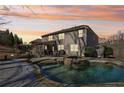 A backyard pool featuring a spa and waterfall, surrounded by stone and a screened-in porch under a colorful sunset at 4375 Maverick Nw Ln, Kennesaw, GA 30152