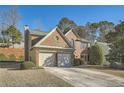 Brick home featuring an attached two-car garage and mature landscaping at 9185 Brockham Way, Alpharetta, GA 30022