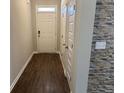 Inviting hallway with wood floors, a decorative stone accent wall, coat closet, and a bright front door at 11978 Lovejoy Crossing Way, Hampton, GA 30228