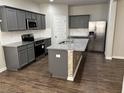 Modern kitchen with gray cabinets, granite countertops, stainless steel appliances, and an island with a sink at 11978 Lovejoy Crossing Way, Hampton, GA 30228