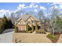 Elegant two-story home with brick accents, complemented by lush landscaping, mature trees, and a welcoming driveway at 5245 Wilshire Xing, Cumming, GA 30040