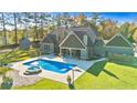 Gorgeous backyard with a sparkling pool and spa, surrounded by a lush green lawn and mature trees at 650 New Morn Dr, Hampton, GA 30228