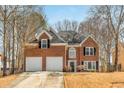 Classic brick home featuring a two-car garage, complemented by mature trees and a well-kept lawn at 4872 Thicket Path, Acworth, GA 30102