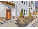 Inviting front entrance with an orange door, white siding, stone accents, and manicured landscaping at 488 Hammons Way, Atlanta, GA 30315