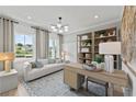 Bright home office featuring a modern light fixture, built-in shelving, and a comfortable seating area at 6094 Marigold Way, Atlanta, GA 30349