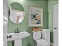 Stylish powder room with a pedestal sink, round mirror, and vibrant green walls at 114 Asher Dr, Carrollton, GA 30116