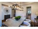 A dining room with a wood table, white chairs, modern chandelier, and an accent mirror at 264 Rockledge Sw Bnd, Powder Springs, GA 30127